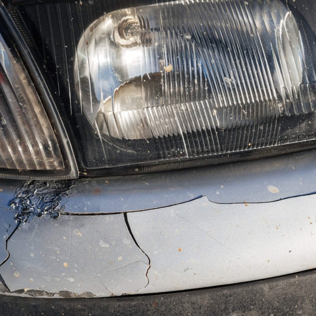 altes-auto-nach-einem-unfall-mit-beschadigter-zerknitterter-stossstange-scaled